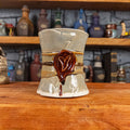 Front view of a handmade Scroll Mug designed to look like an old rolled parchment with a light grey base, a light brown ribbon, a dark brown cord and a dark red wax seal featuring a vampire emblem.