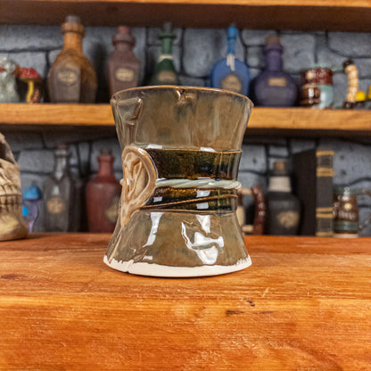 Three-quarter right side view of a handmade Scroll Mug designed to look like an old rolled parchment with a brown base, a brown-green ribbon, a light green cord and a beige wax seal featuring a vampire emblem.