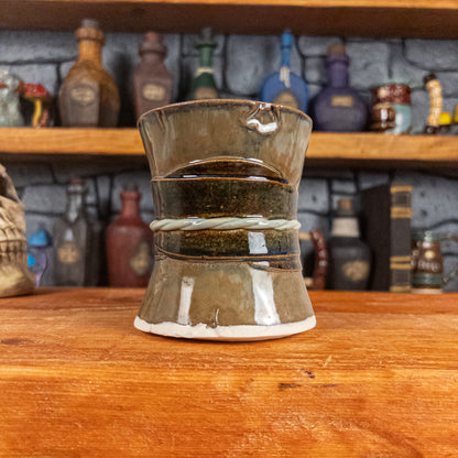 Back view of a handmade Scroll Mug designed to look like an old rolled parchment with a brown base, a brown-green ribbon and a light green cord.