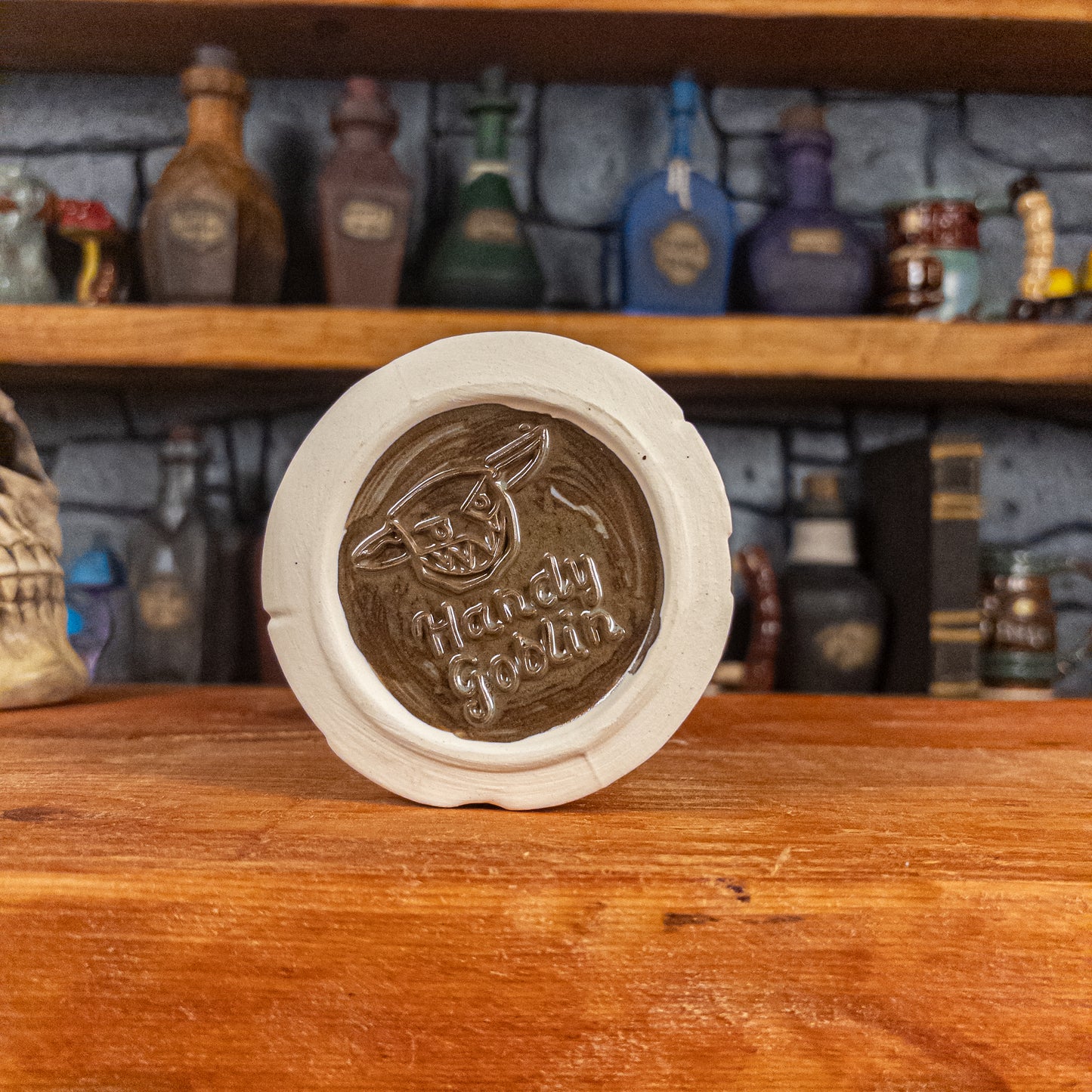 Bottom view of a handmade Scroll Mug with the Handy Goblin logo embossed in the centre, featuring a brown base.