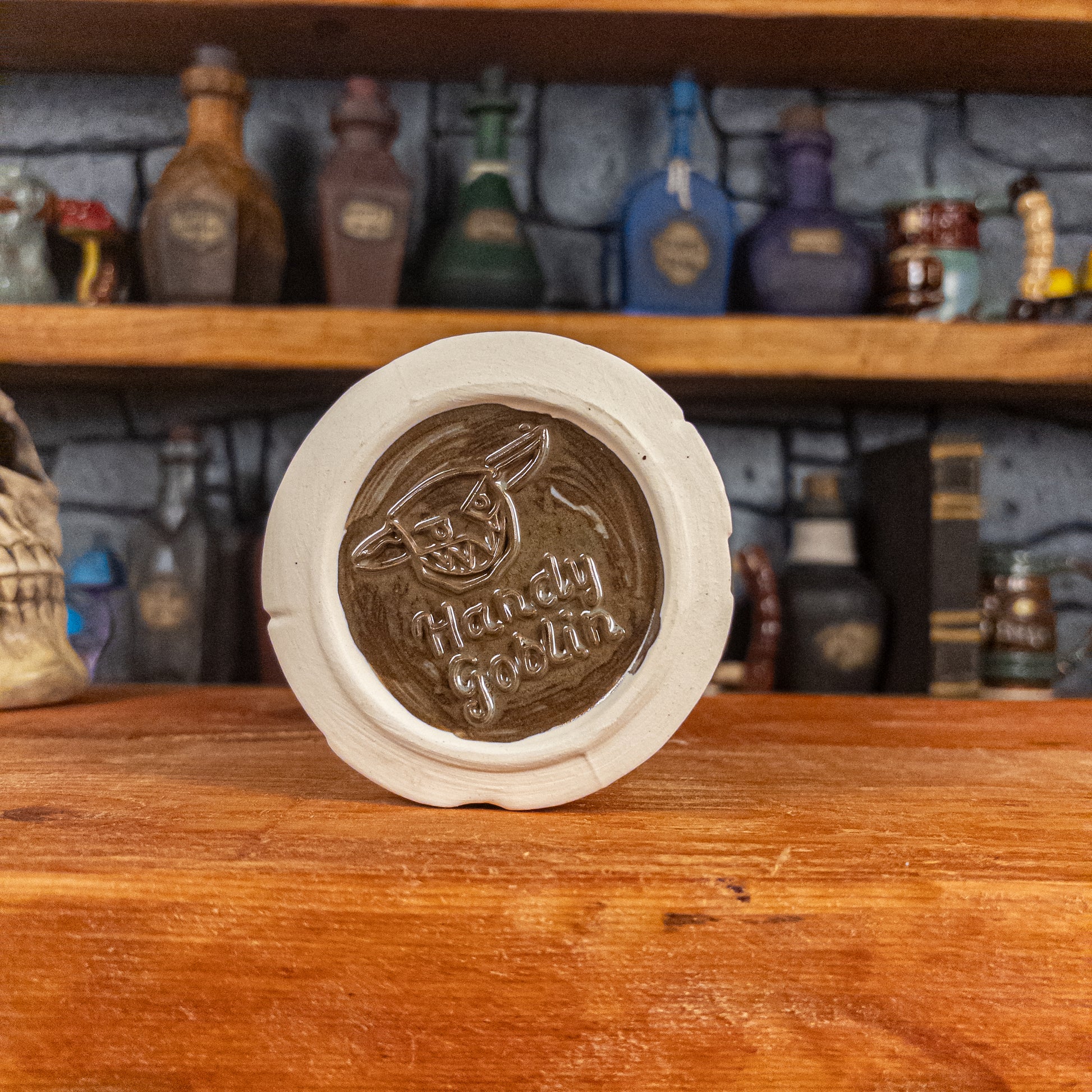 Bottom view of a handmade Scroll Mug with the Handy Goblin logo embossed in the centre, featuring a brown base.