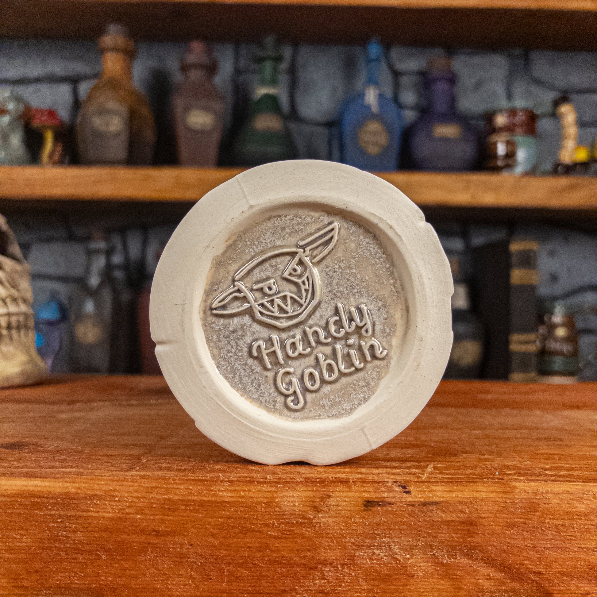 Bottom view of a handmade Scroll Mug with the Handy Goblin logo embossed in the centre, featuring a grey base.