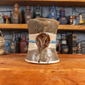 Front view of a handmade Scroll Mug designed to look like an old rolled parchment with a speckled dark brown base, an alabaster ribbon, a light blue cord and a reddish-brown wax seal featuring a vampire emblem.