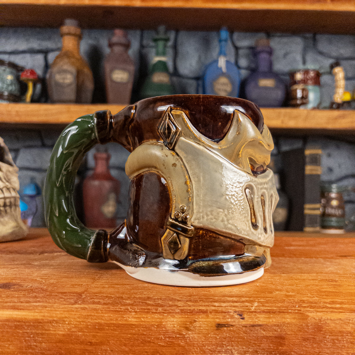 The left side view of a handmade Knight Helmet Mug with a brown, beige, and grey armour design, featuring ornamental rivets and a detailed green handle.