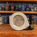 Bottom view of a handmade Knight Helmet Mug with the Handy Goblin logo embossed in the centre, featuring a grey base.