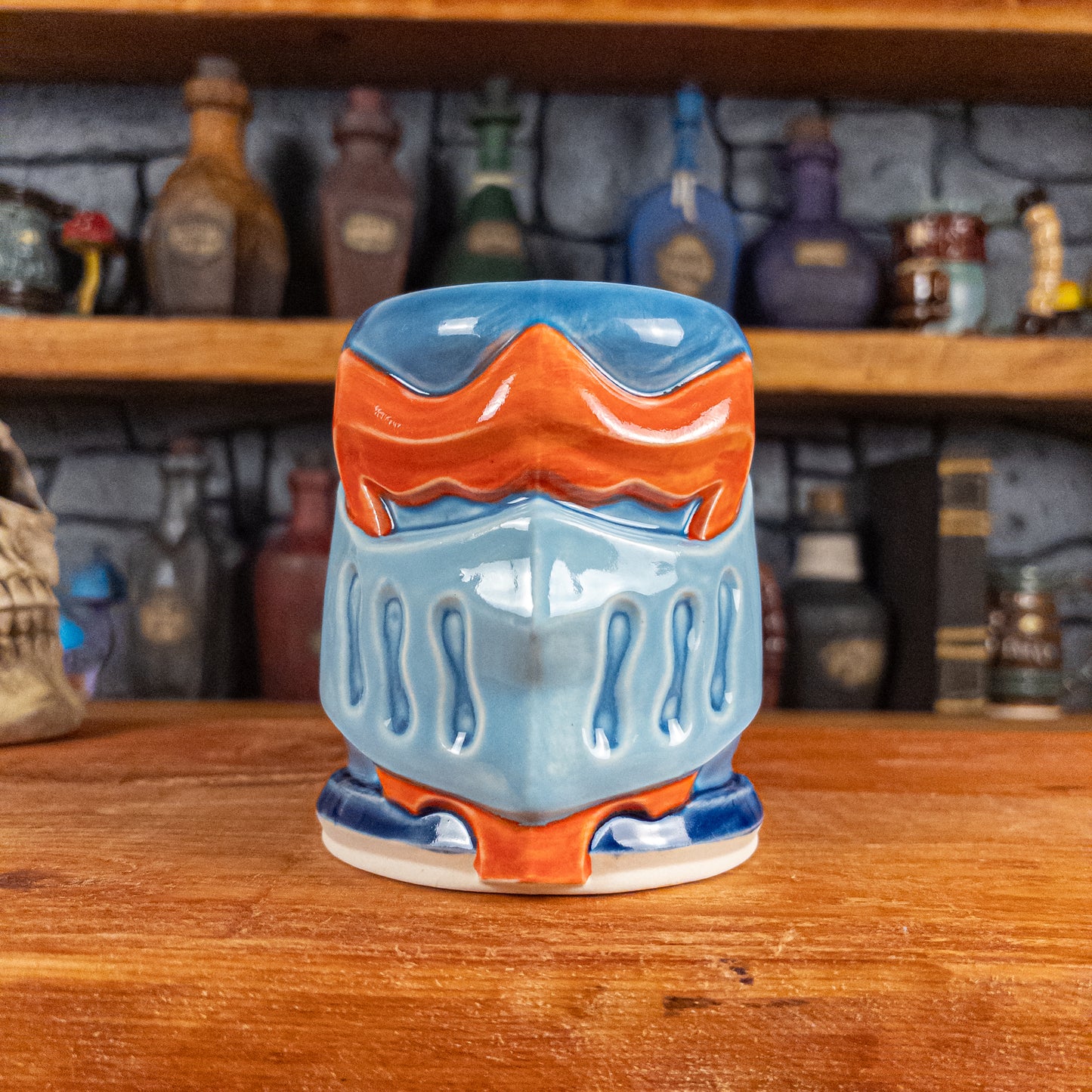 Front view of a handmade Knight Helmet Mug with a light blue, blue and red-orange armour design.