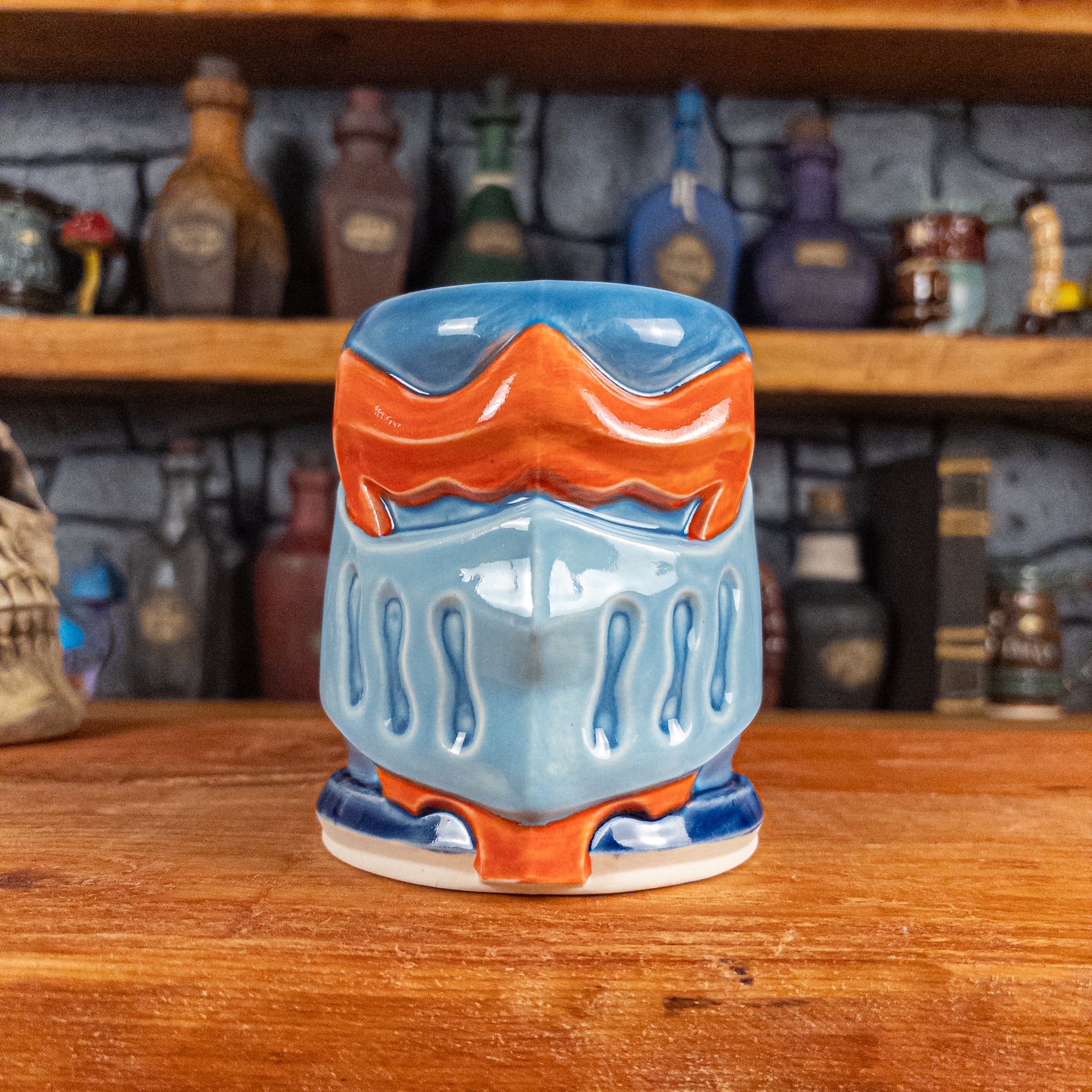 Front view of a handmade Knight Helmet Mug with a light blue, blue and red-orange armour design.