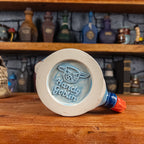 Bottom view of a handmade Knight Helmet Mug with the Handy Goblin logo embossed in the centre, featuring a light blue base.