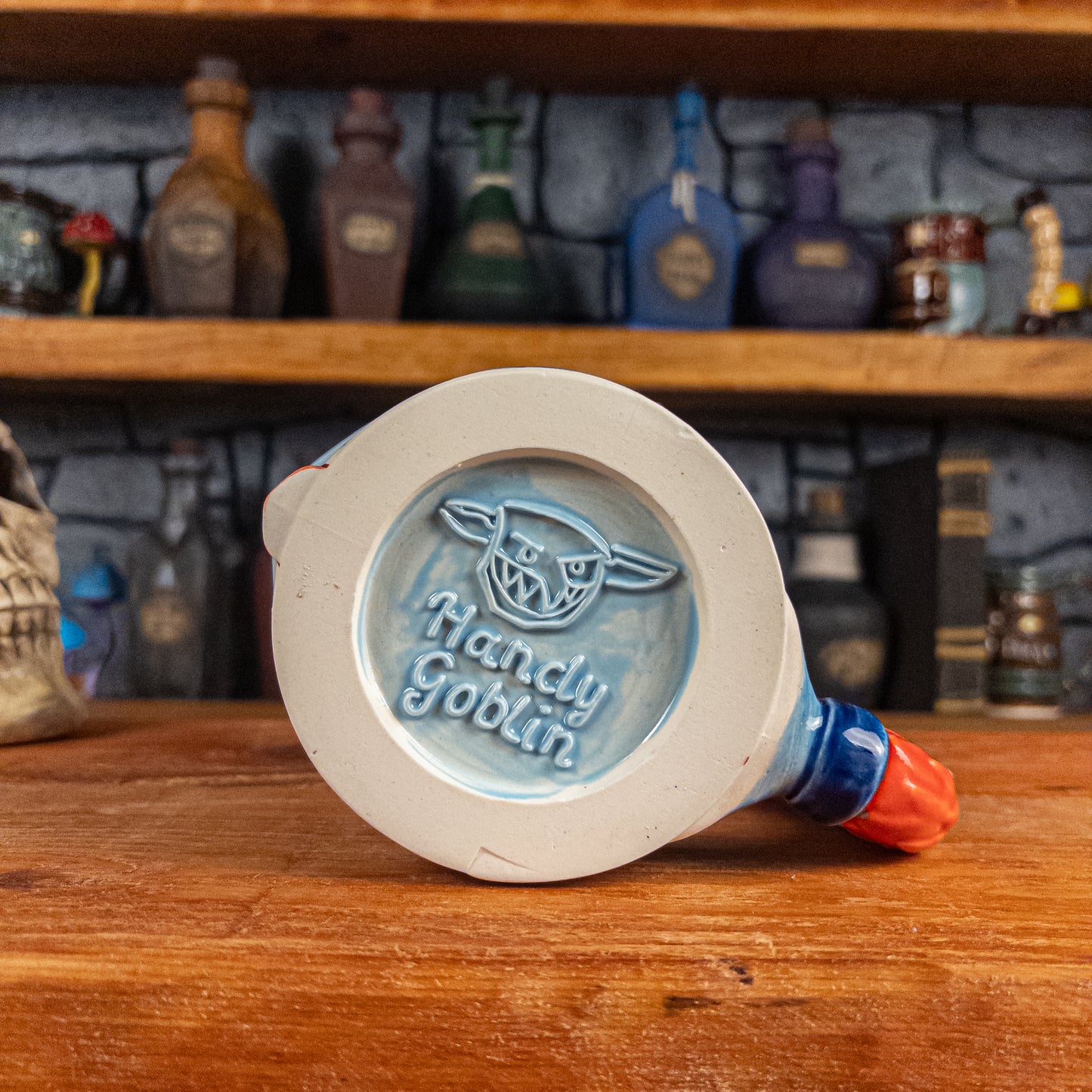 Bottom view of a handmade Knight Helmet Mug with the Handy Goblin logo embossed in the centre, featuring a light blue base.