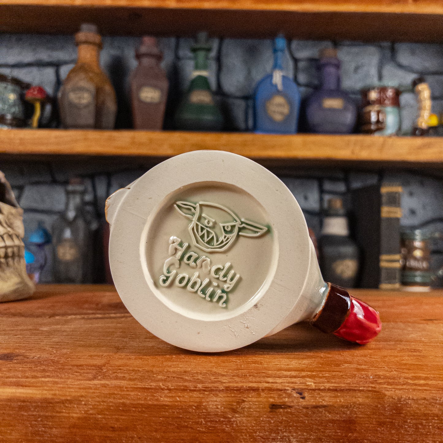 Bottom view of a handmade Knight Helmet Mug with the Handy Goblin logo embossed in the centre, featuring a transparent green base.