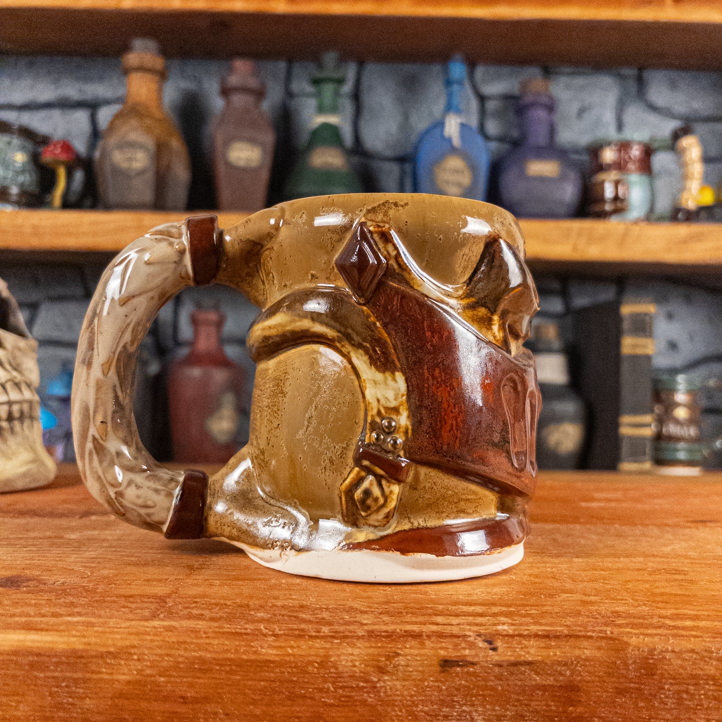 The left side view of a handmade Knight Helmet Mug with a brown and rusted armour design and brown eye slits, featuring ornamental rivets and a detailed sandy handle.