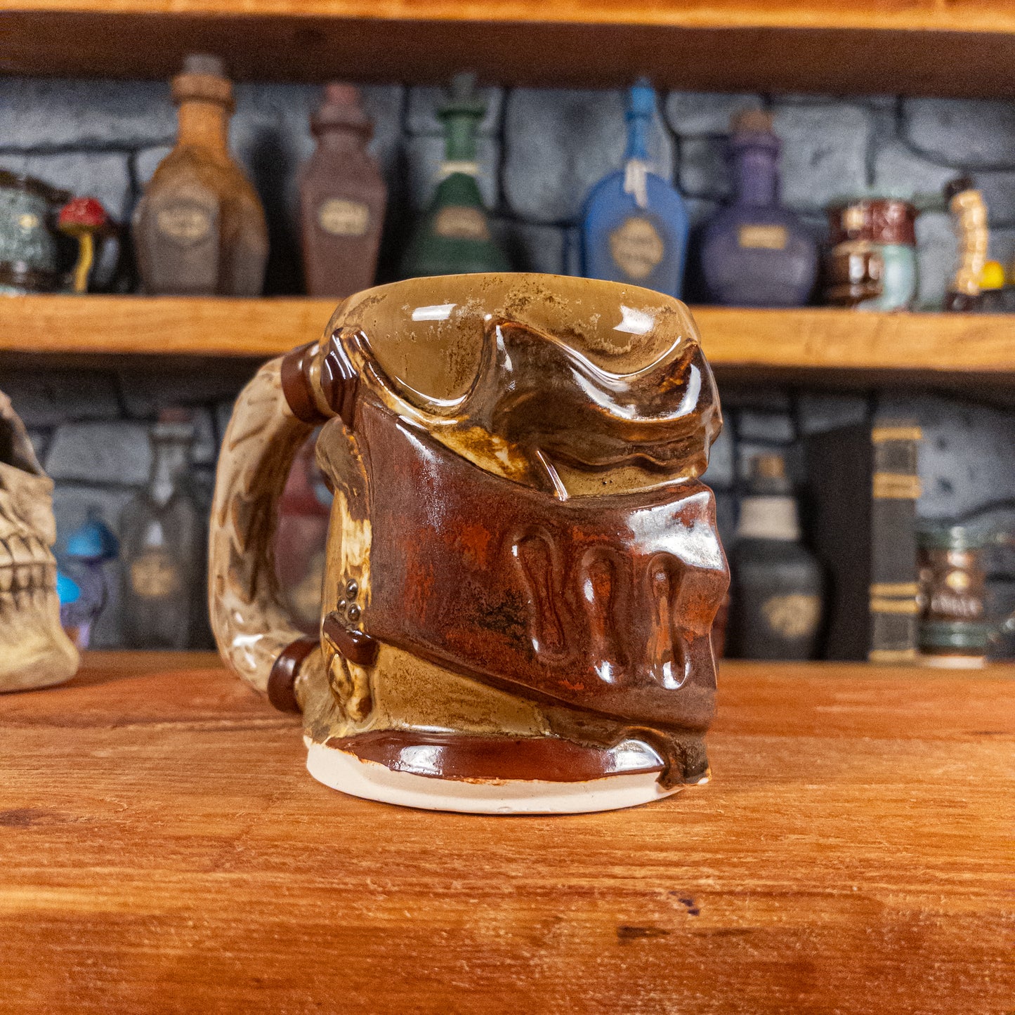 Three-quarter left side view of a handmade Knight Helmet Mug with a brown and rusted armour design and brown eye slits, featuring ornamental rivets and a detailed sandy handle.