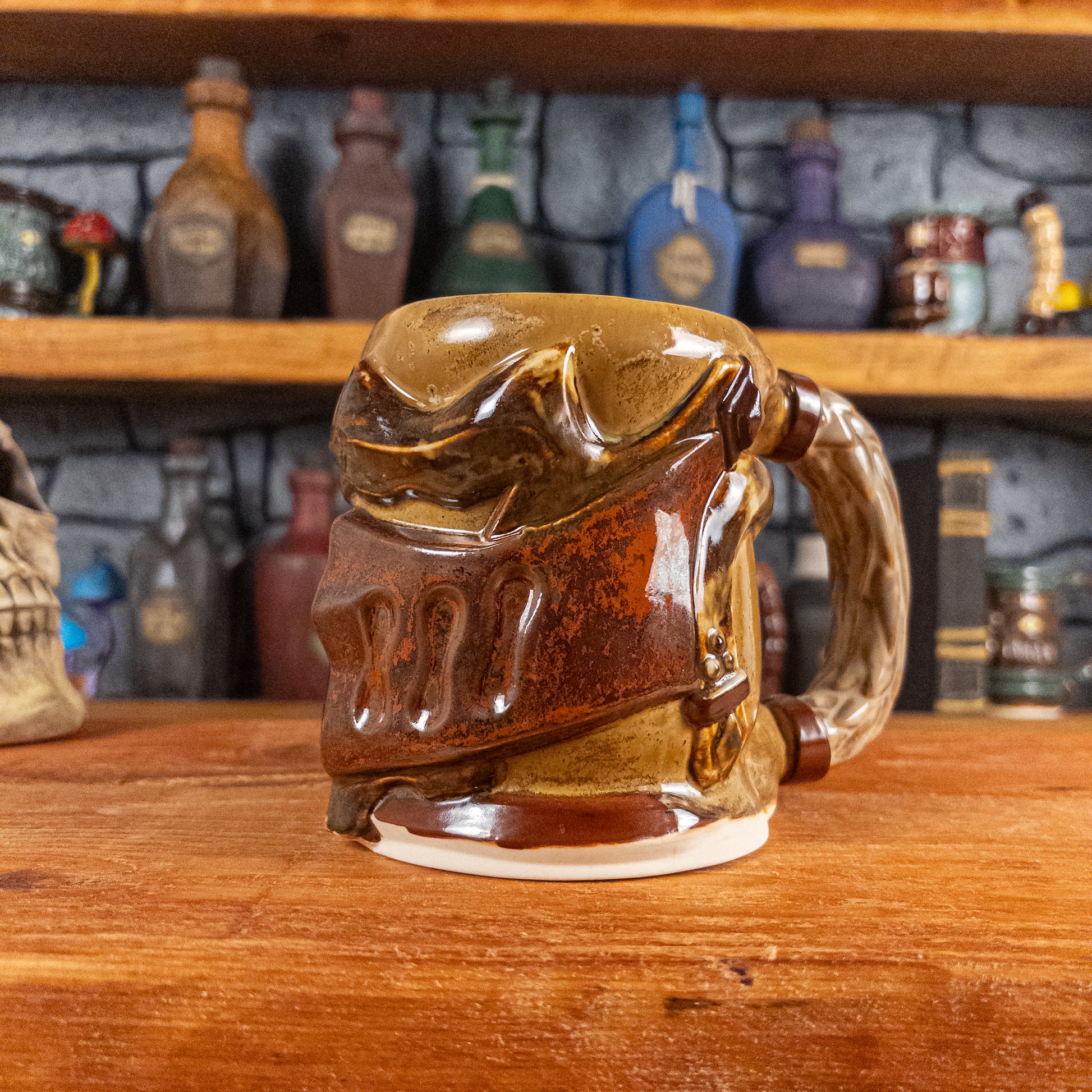 Three-quarter right side view of a handmade Knight Helmet Mug with a brown and rusted armour design and brown eye slits, featuring ornamental rivets and a detailed sandy handle.