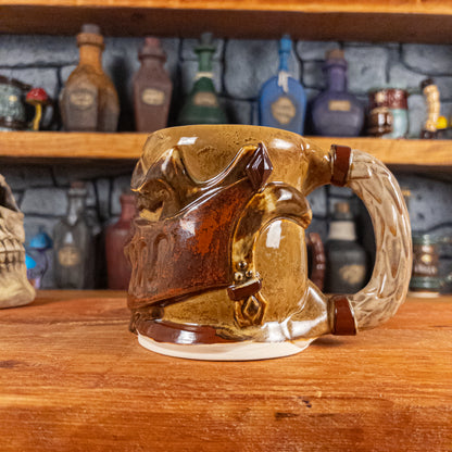 The right side view of a handmade Knight Helmet Mug with a brown and rusted armour design and brown eye slits, featuring ornamental rivets and a detailed sandy handle.