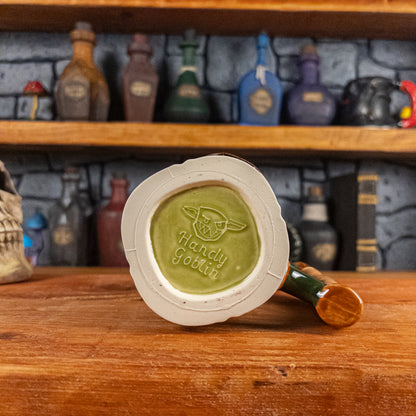 Bottom view of a handmade Dwarven Mug with the 'Handy Goblin' logo embossed in the center, featuring a light green base.