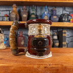 Left side view of a handmade Dwarven Mug designed to look like a wine red and light sand barrel with intricate rune carvings, a partial dark brown dwarf face, and a hammer and anvil design, showing the detailed handle.
