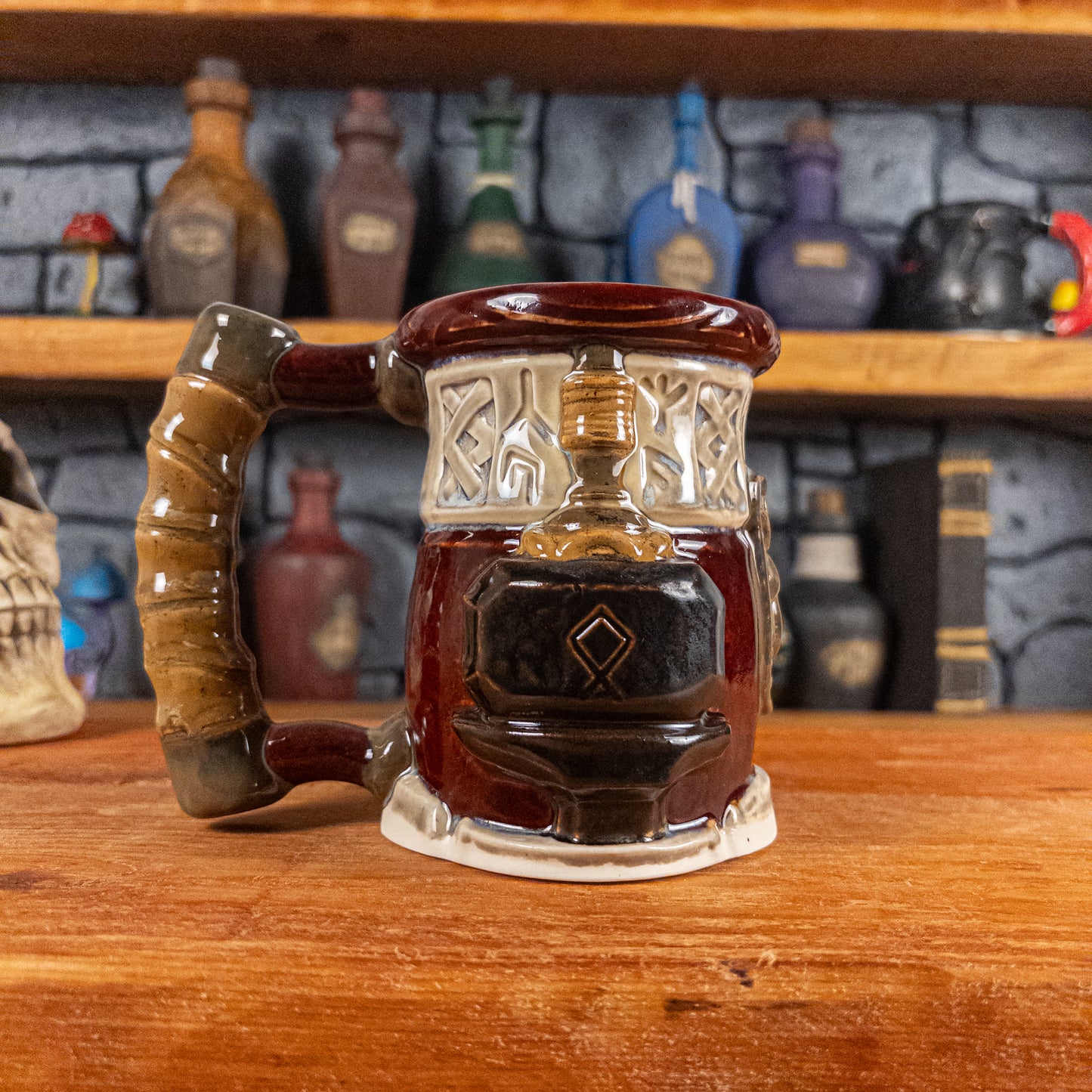 Left side view of a handmade Dwarven Mug designed to look like a wine red and light sand barrel with intricate rune carvings, a partial dark brown dwarf face, and a hammer and anvil design, showing the detailed handle.
