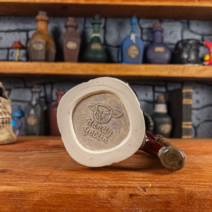Bottom view of a handmade Dwarven Mug with the 'Handy Goblin' logo embossed in the center, featuring a light sand base.