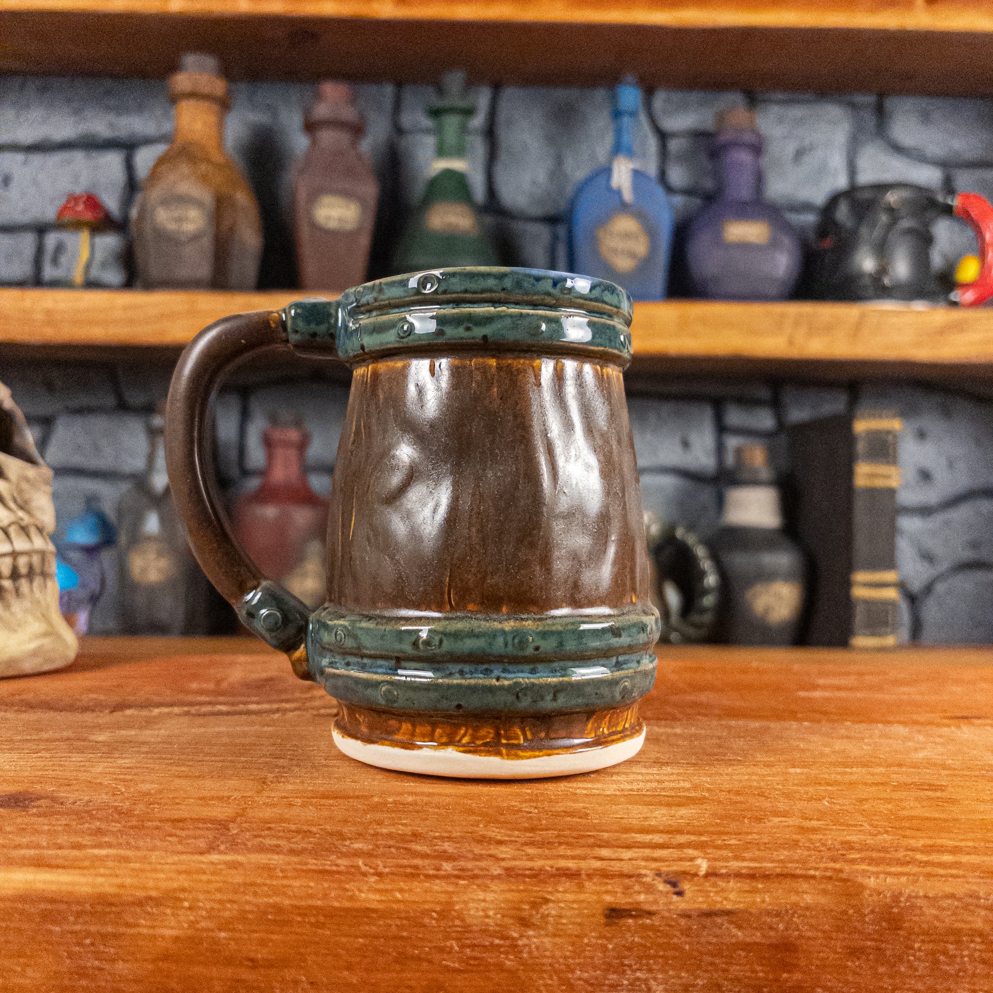 Back view of a handmade Mimic Mug designed to look like a brown wooden barrel with dark green bands, showing the handle.
