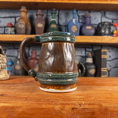 Back view of a handmade Mimic Mug designed to look like a brown wooden barrel with dark green bands, showing the handle.