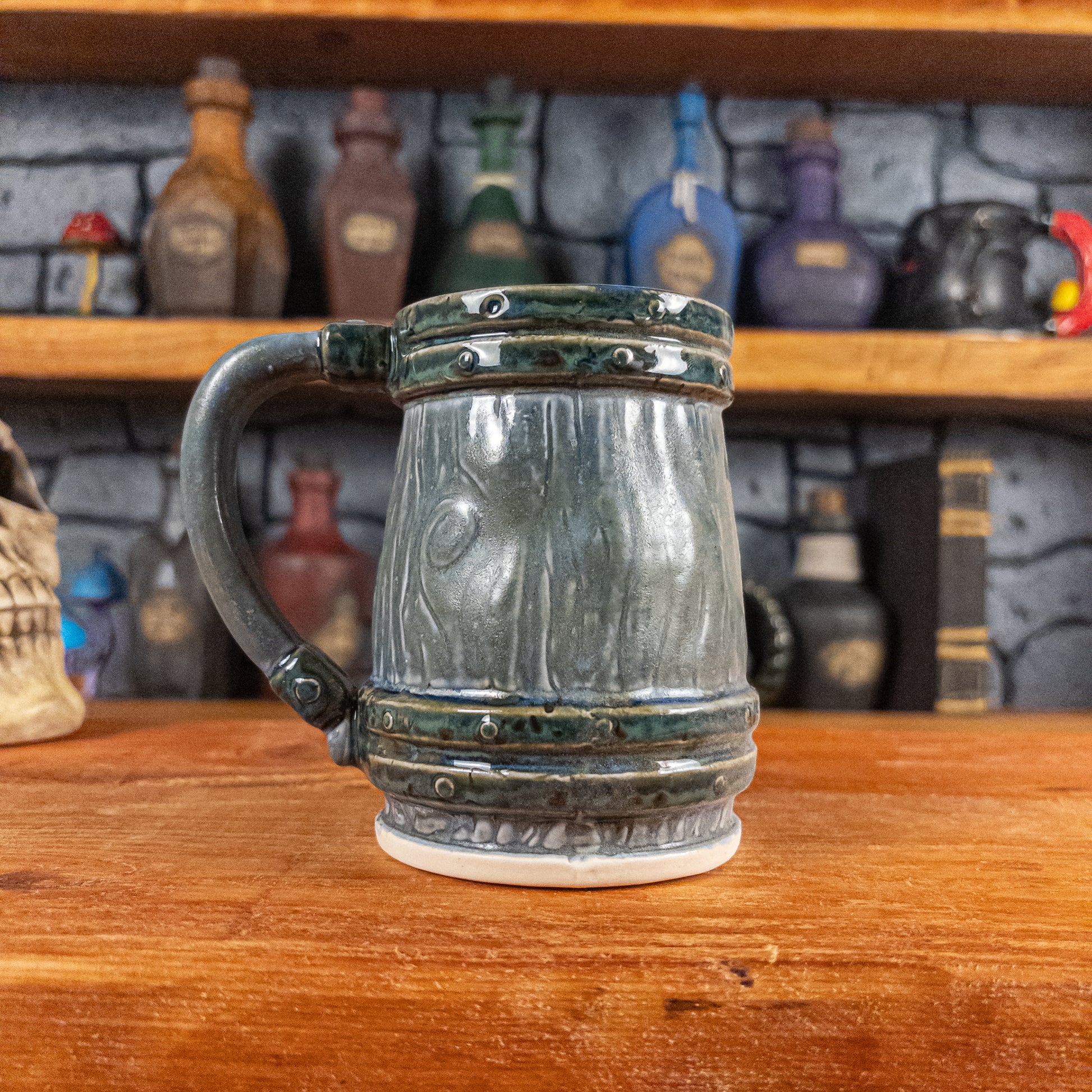 Back view of a handmade Mimic Mug designed to look like a greenish-blue wooden barrel with dark brown bands, showing the handle.
