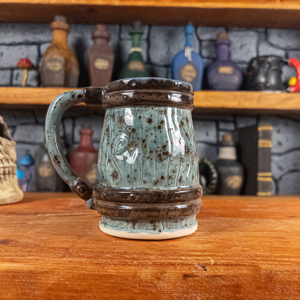Back view of a handmade Mimic Mug designed to look like a speckled light blue wooden barrel with dark brown bands, showing the handle.