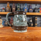 Back view of a handmade Mimic Mug designed to look like a speckled light blue wooden barrel with dark brown bands, showing the handle.