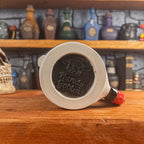 Bottom view of a handmade Knight Helmet Mug with the Handy Goblin logo embossed in the centre, featuring a matte black base.