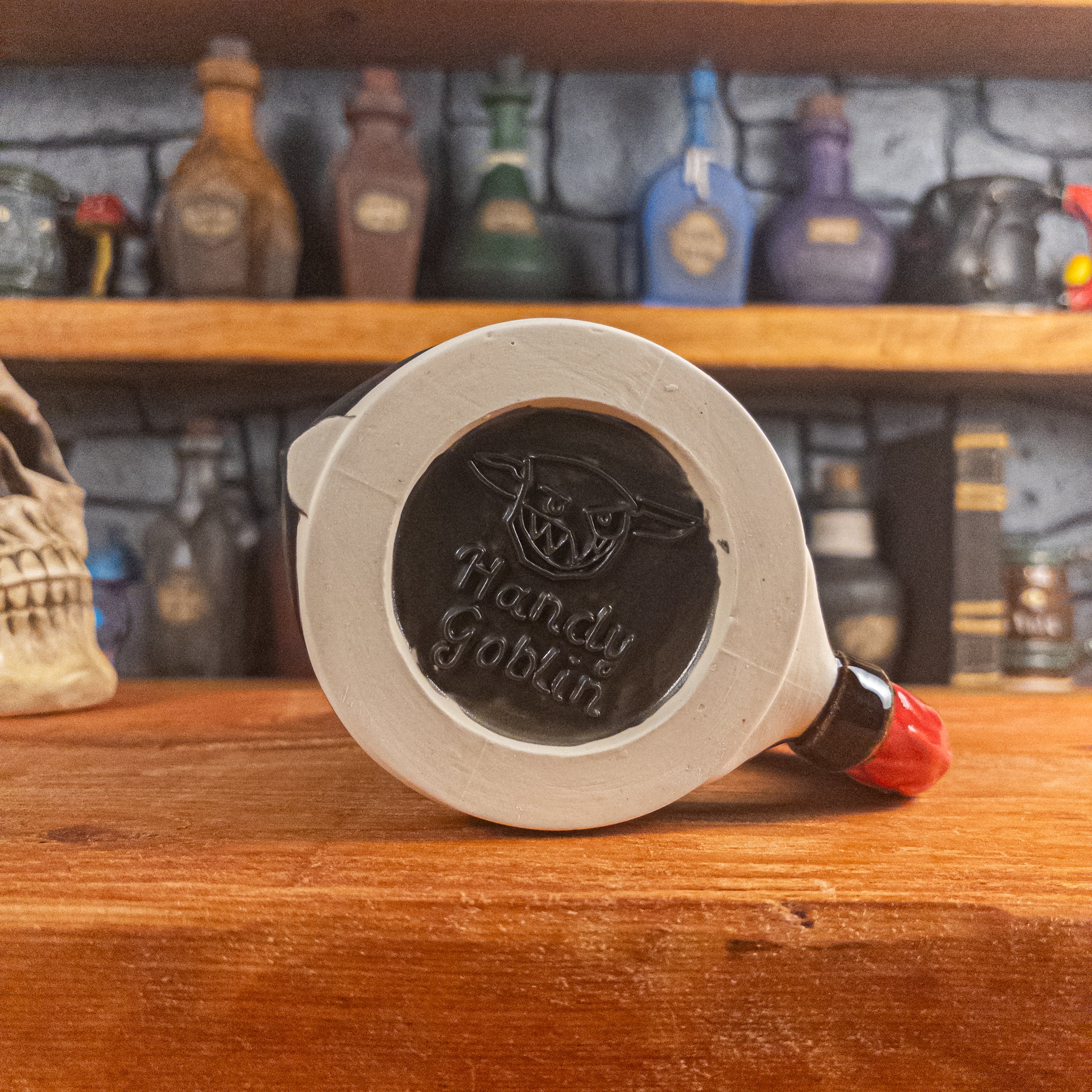 Bottom view of a handmade Knight Helmet Mug with the Handy Goblin logo embossed in the centre, featuring a matte black base.