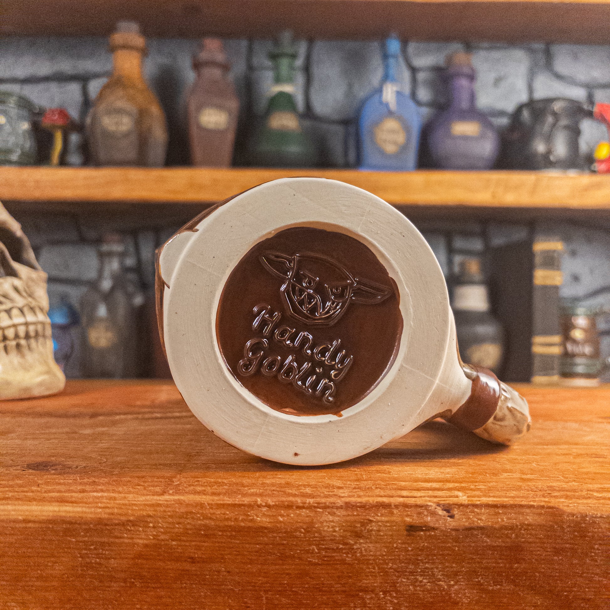 Bottom view of a handmade Knight Helmet Mug with the Handy Goblin logo embossed in the centre, featuring a brown base.