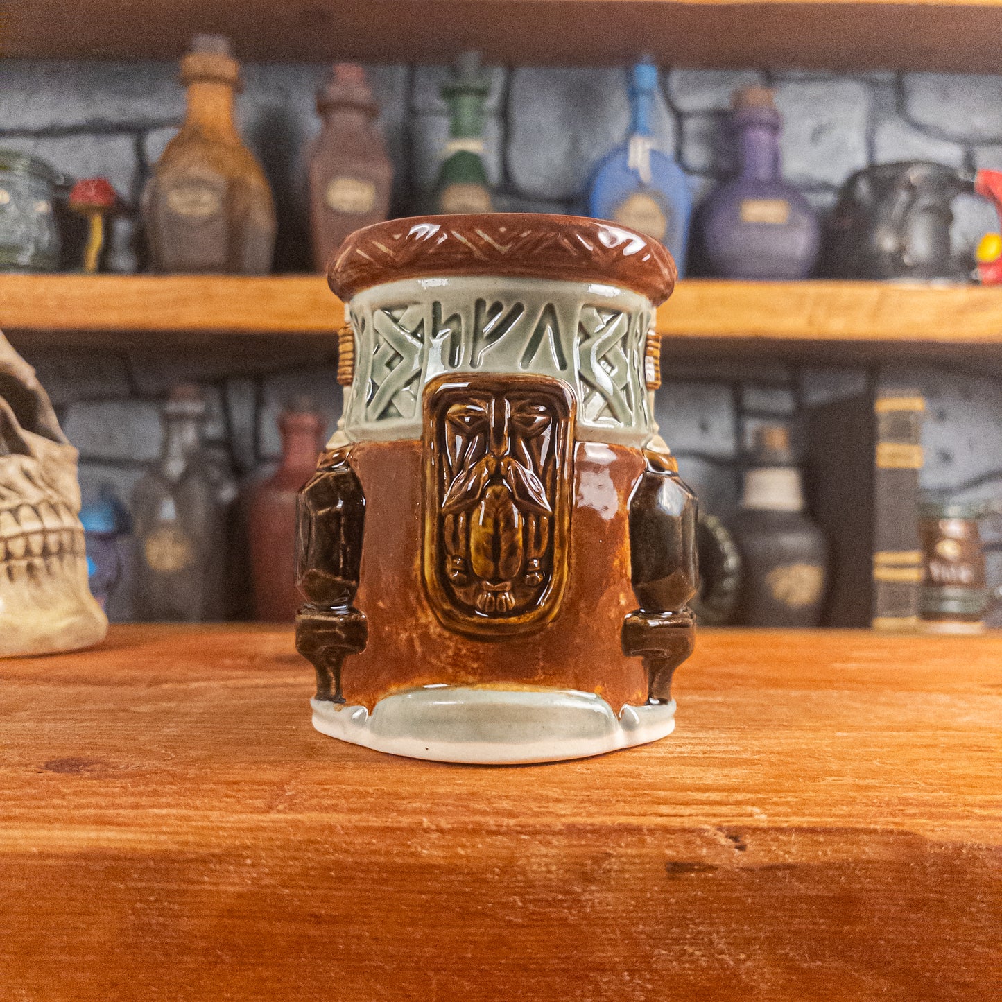 Front view of a handmade Dwarven Mug designed to look like a light green and reddish-brown barrel with intricate rune carvings, a dwarf face, and a partial hammer and anvil design.