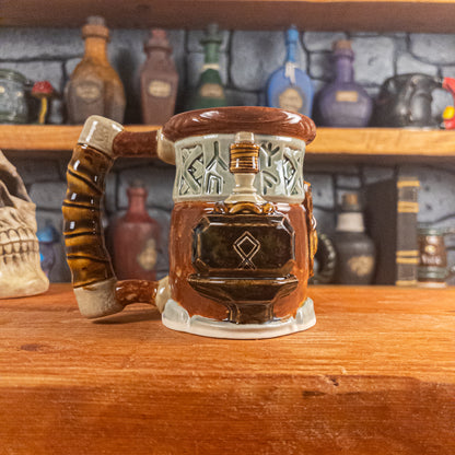 Left side view of a handmade Dwarven Mug designed to look like a light green and reddish-brown barrel with intricate rune carvings, a partial dwarf face, and a hammer and anvil design, showing the detailed handle.