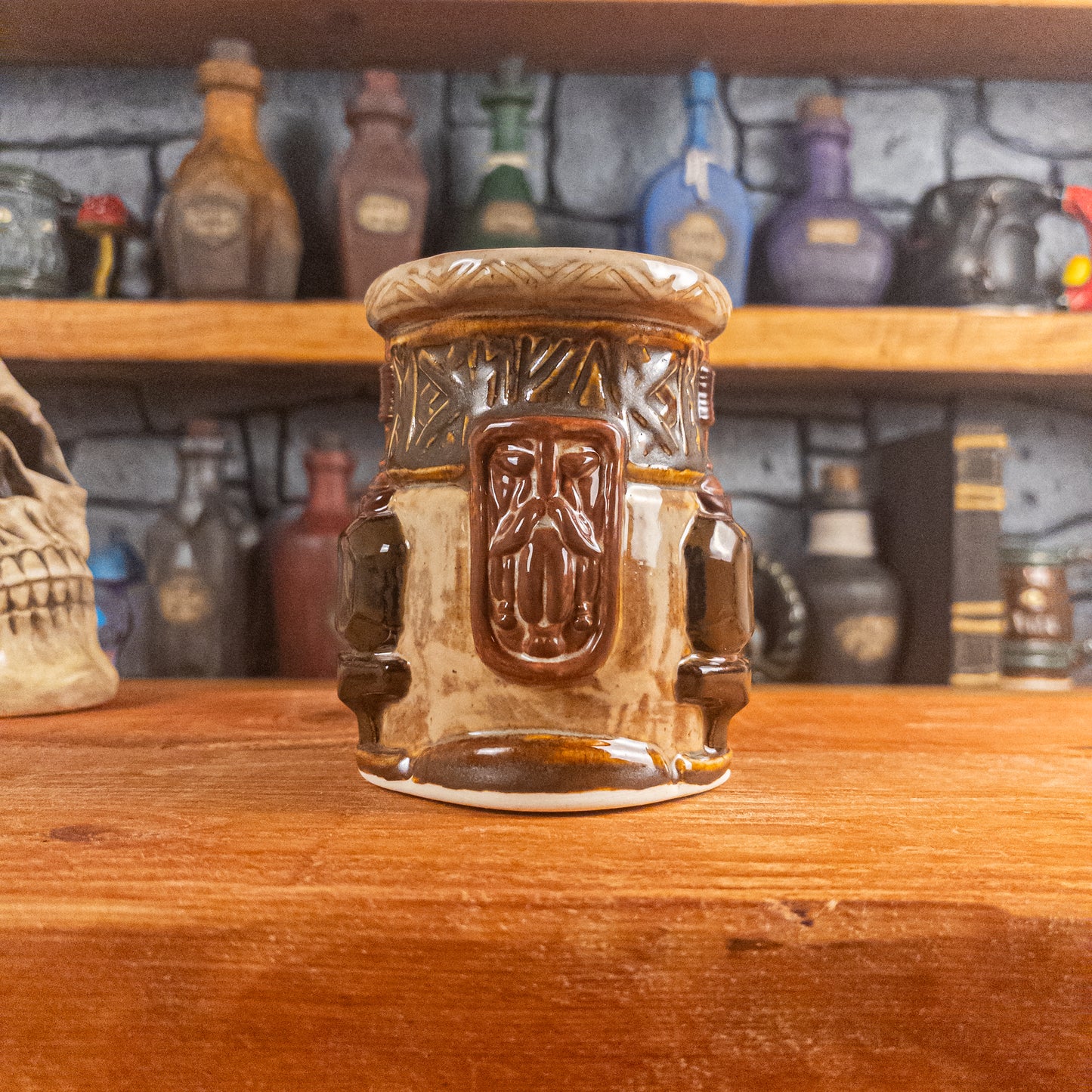 Front view of a handmade Dwarven Mug designed to look like a beige and dark brown barrel with intricate rune carvings, a brown dwarf face, and a partial hammer and anvil design, showing the detailed handle.