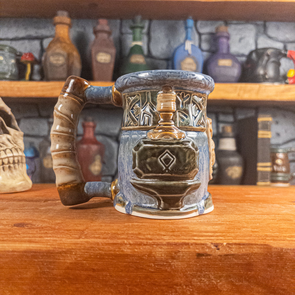 Left side view of a handmade Dwarven Mug designed to look like a white-blue and brown-blue barrel with intricate rune carvings, a partial beige dwarf face, and a hammer and anvil design, showing the detailed handle.