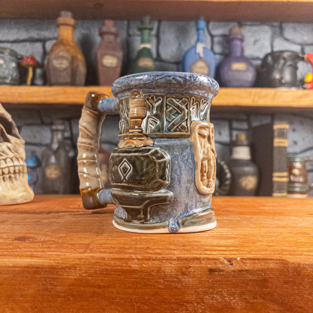 Three-quarter left side view of a handmade Dwarven Mug designed to look like a white-blue and brown-blue barrel with intricate rune carvings, a beige dwarf face, and a hammer and anvil design, showing the detailed handle.