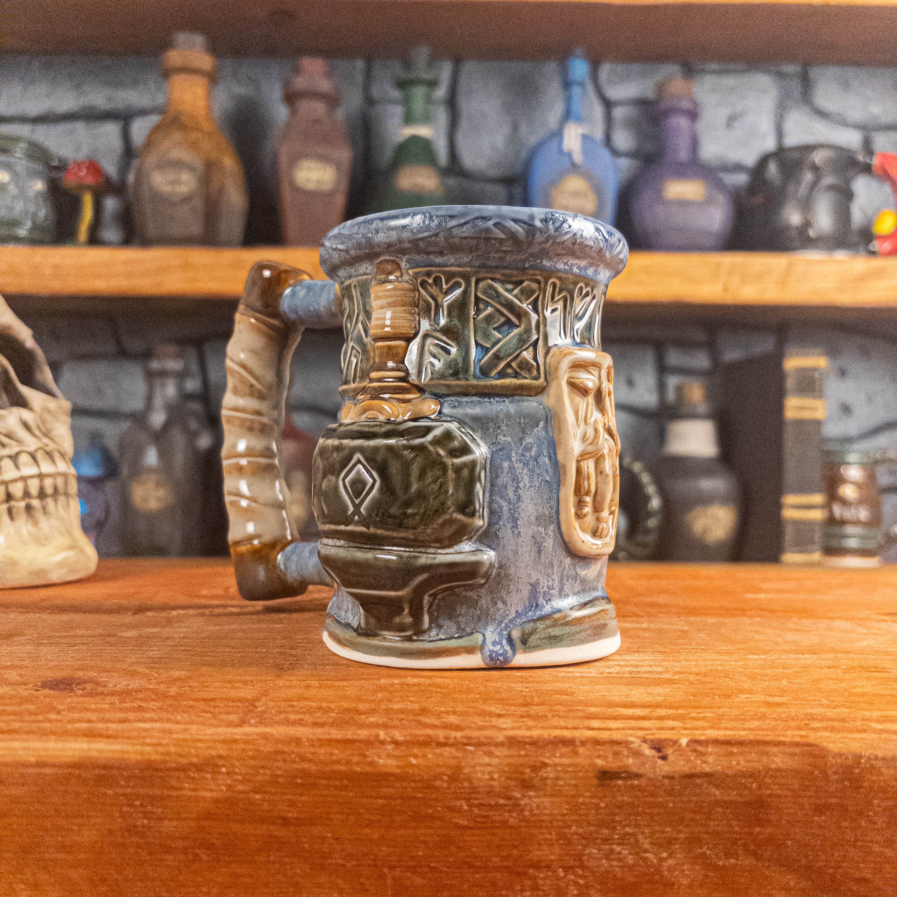 Three-quarter left side view of a handmade Dwarven Mug designed to look like a white-blue and brown-blue barrel with intricate rune carvings, a beige dwarf face, and a hammer and anvil design, showing the detailed handle.
