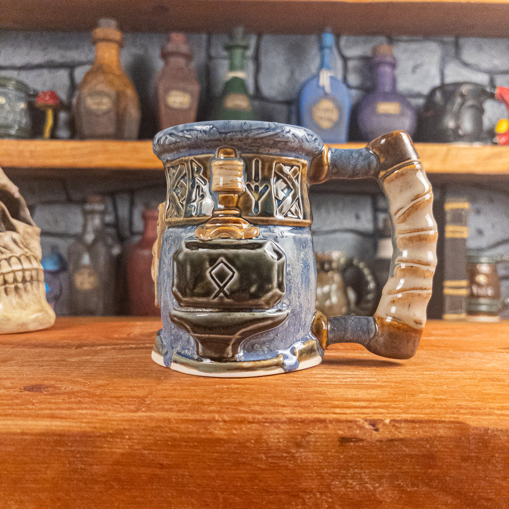 The right side view of a handmade Dwarven Mug designed to look like a white-blue and brown-blue barrel with intricate rune carvings, a partial beige dwarf face, and a hammer and anvil design, showing the detailed handle.